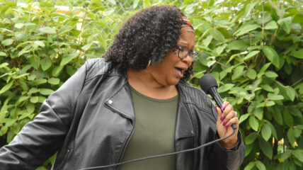 A Black woman with Black shoulder-length hair singing