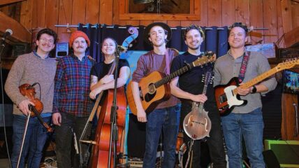 folk band with guitars shown. There are 6 members they are all white.