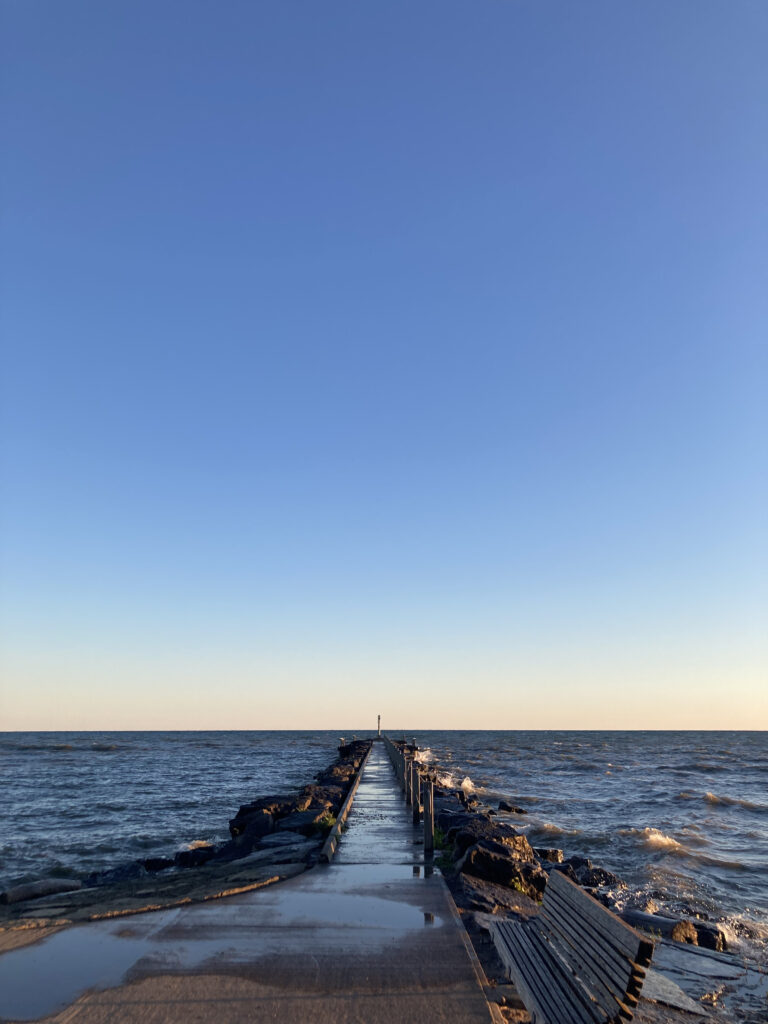 A lake with a board walk that leads to a lighthouse