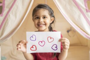 Child holding paper with heart prints