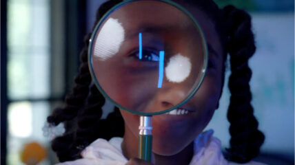 Student looking through a magnifying glass