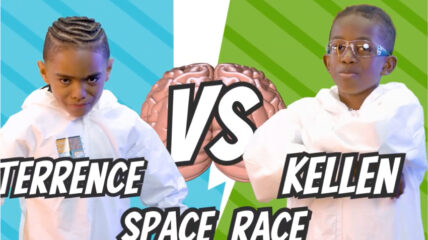 Terrence vs. Kellen in the Space Race. Two students in lab coats prepare to race placing foam representations of microchips onto a circular sliced representation of a silicone wafer