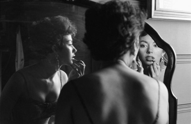 Picture of film and Broadway actor Rita Moreno as she puts on makeup in the mirror.