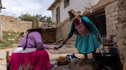 Two women preparing a meal outside on an open fire.