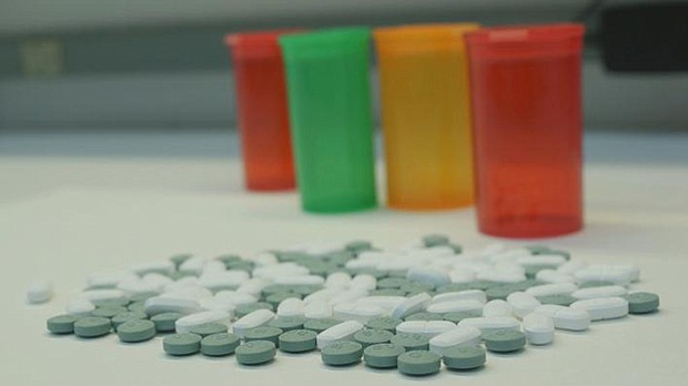 Opioid pills on a table and with empty pill bottles in the background