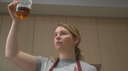 Food technologist looking at liquid in a beaker