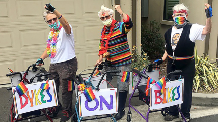 Three seniors on bikes with the colorful rainbow signs that reads "Dykes on Bikes"