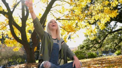 Emma sitting cross-legged under a tree, reaching toward the sunlight. A suicide attempt left Emma paralyzed but propelled her on a mission to help others.