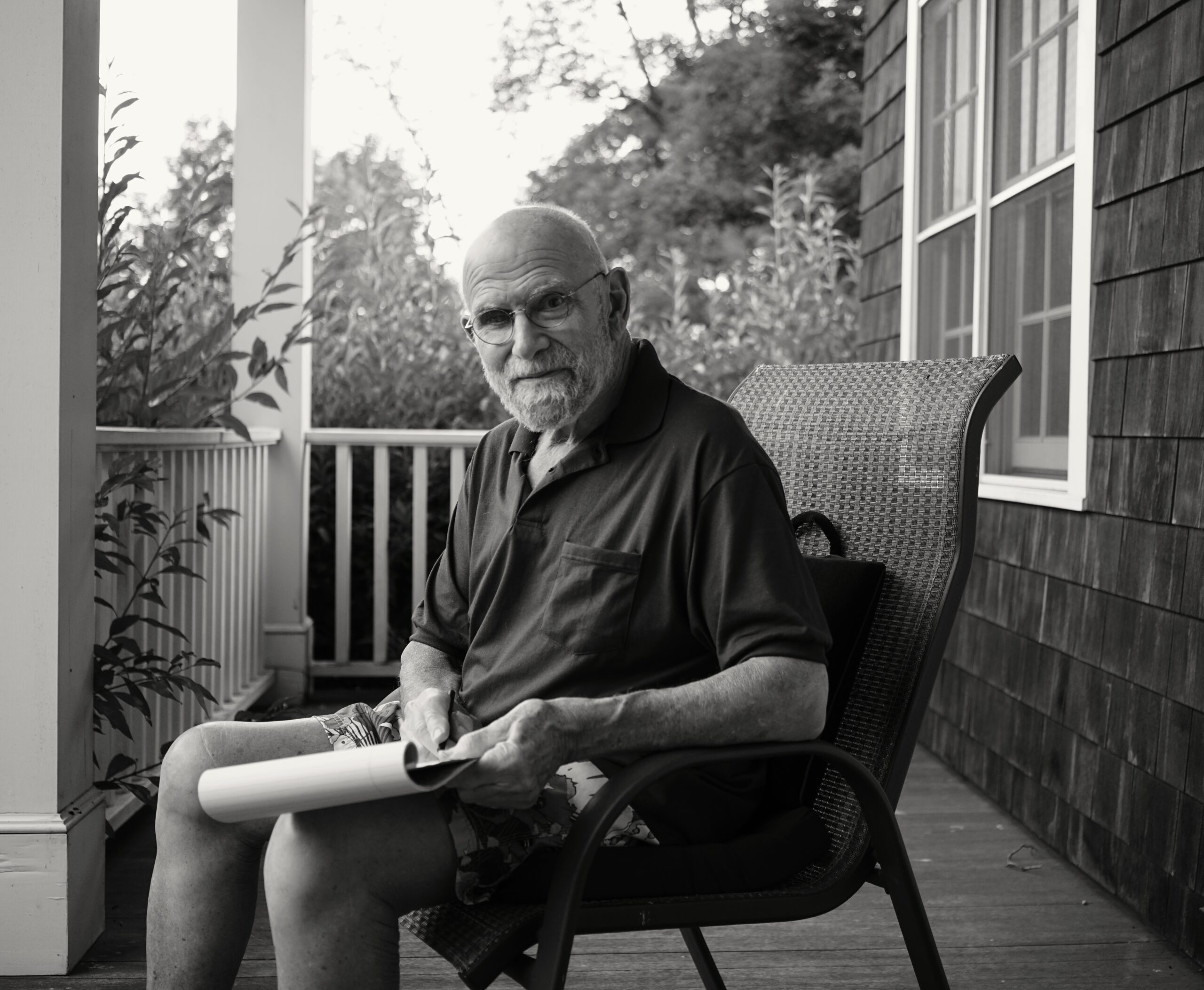 A white older male with a gray beard and mustache wearing oval rimmed glasses, wearing a dark button-down shirt