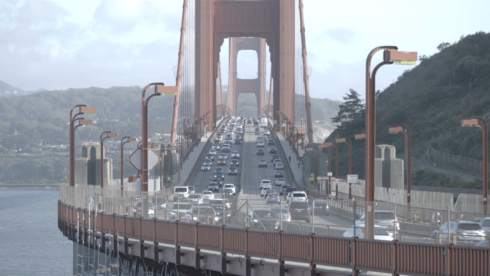 Photo of the Golden Gate Bridge on a sunny day with cars driving on it.
