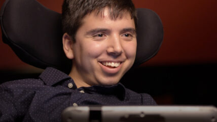 Samuel Habib sitting in his wheelchair smiling at the camera