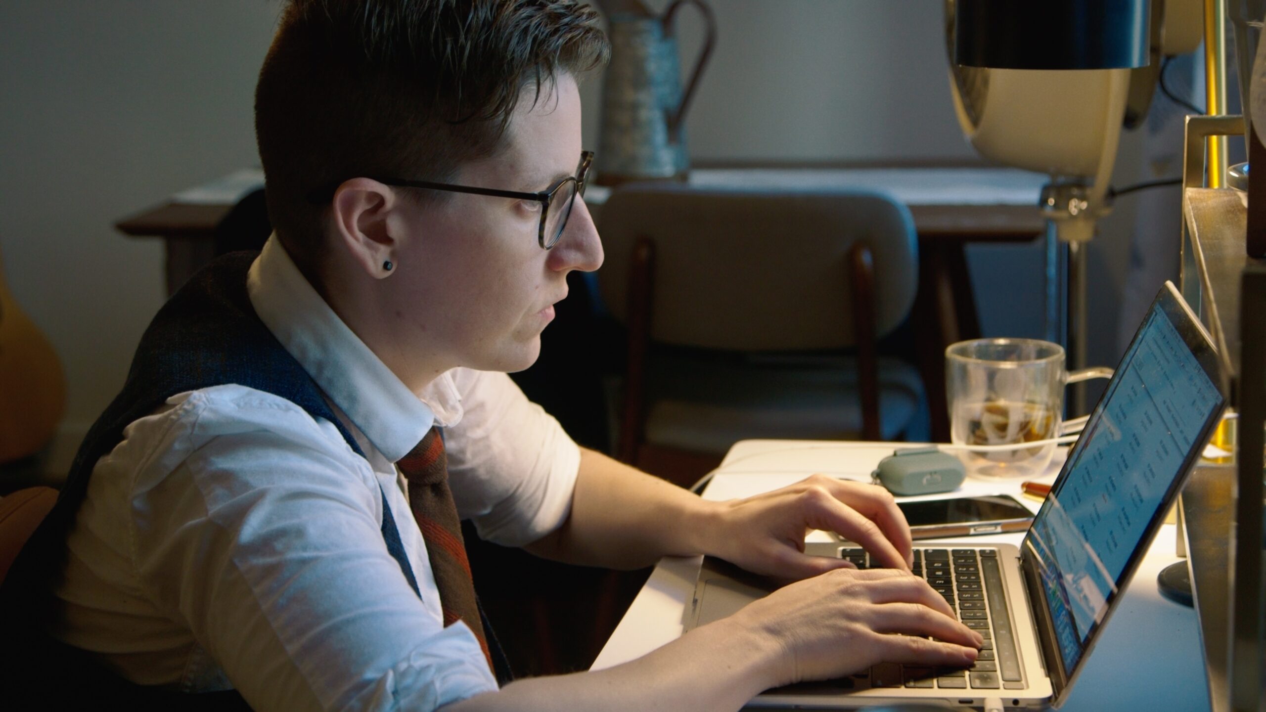 A white woman with short brown hair wearing glasses looks at her computer