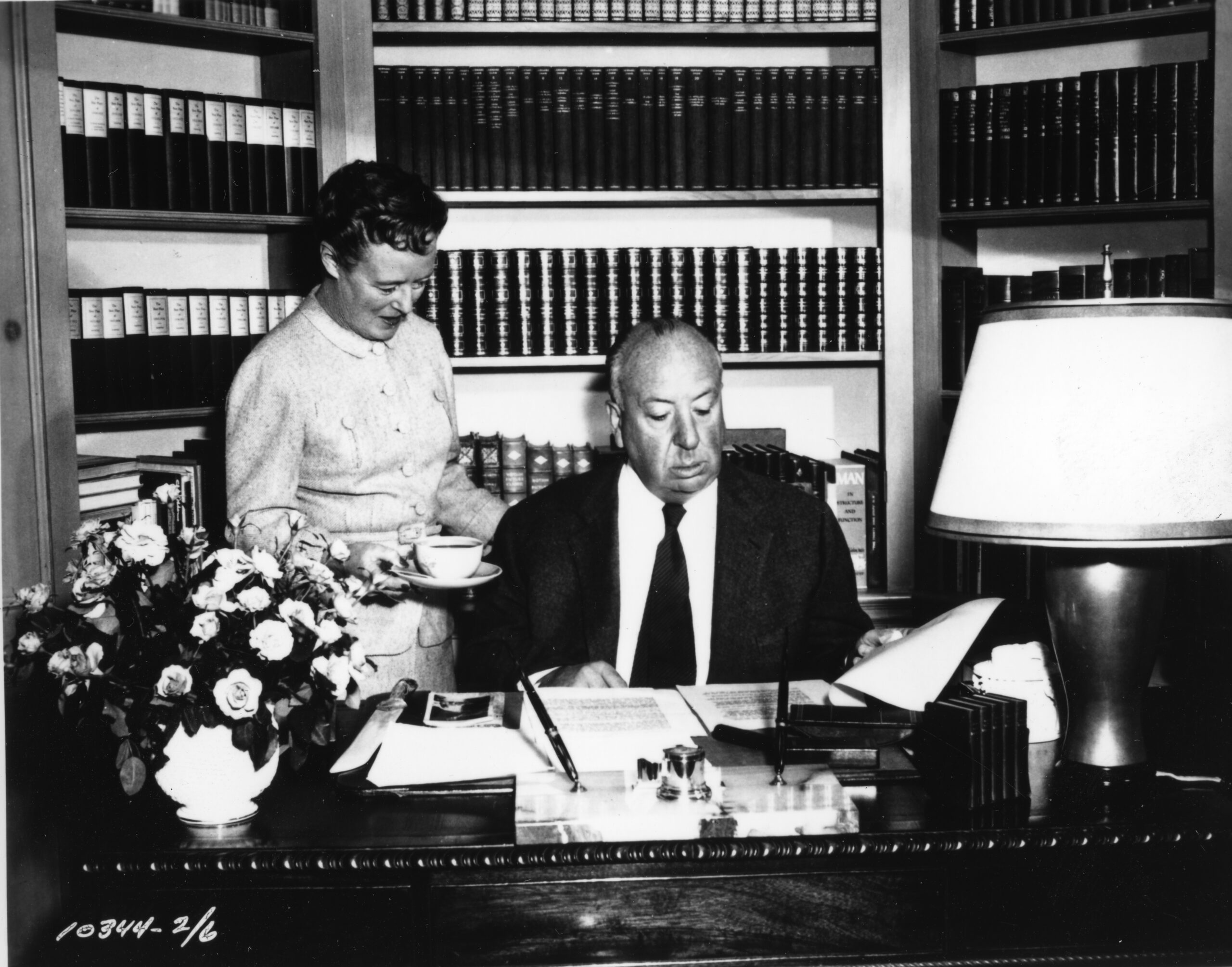 Alfred Hitchcock and his wife in his office looking a papers.