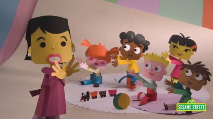 Photo of Animated Paper Teacher and 5 kids on a rug with toys