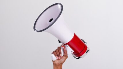 Hand holding up a white and red megaphone