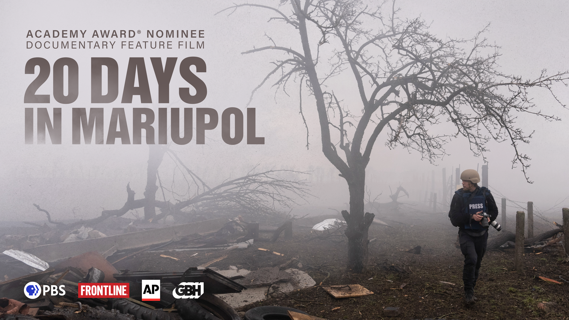 A press photographer walking through rubble of a war torn area