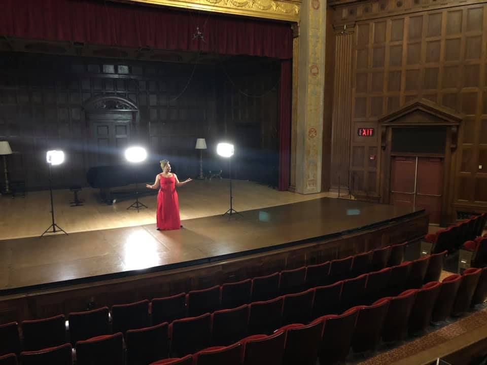 Dancer in a red dress on a stage in a performance hall.