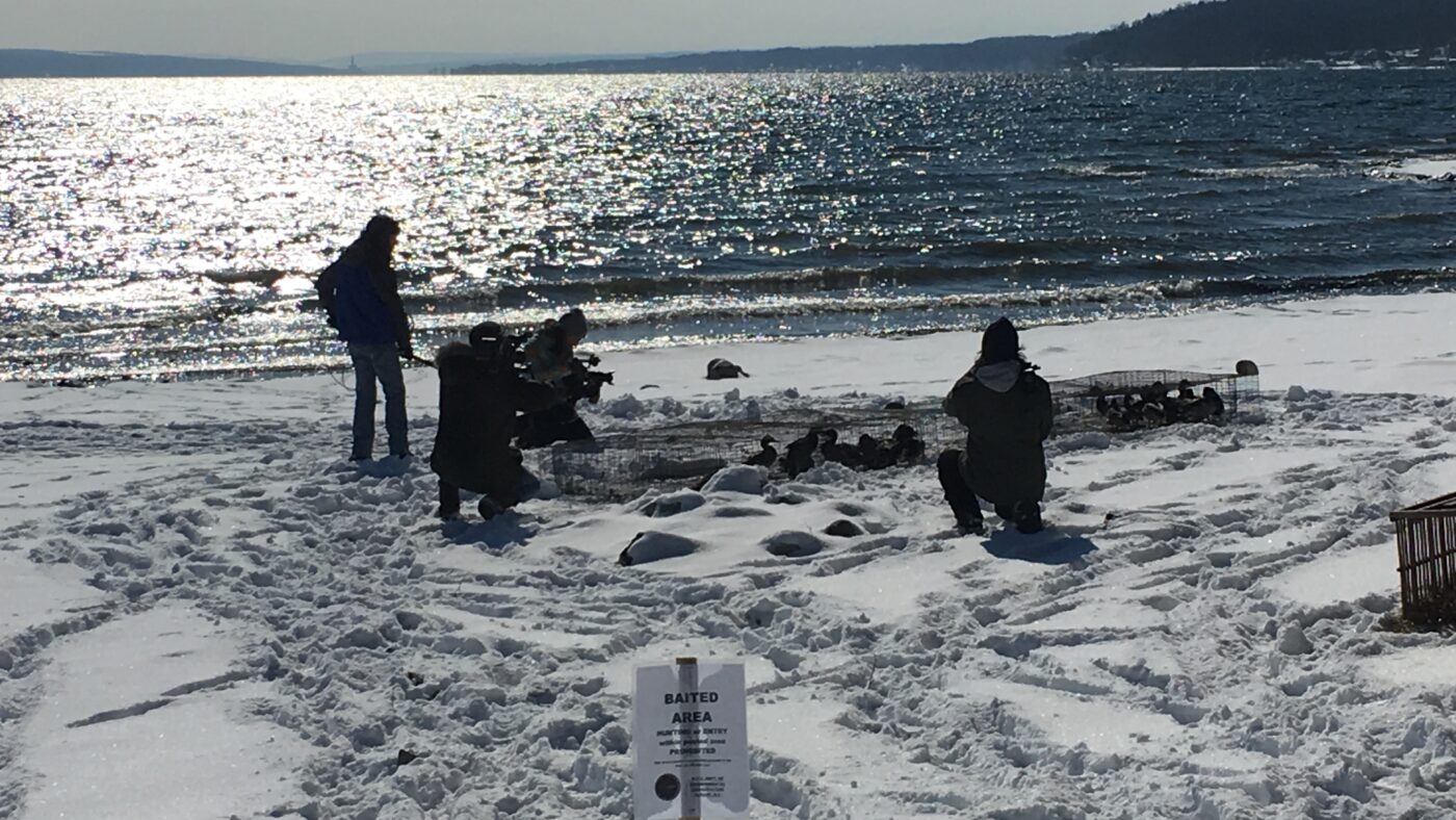 Wildlife technician, TV host and crew by a lake in winter