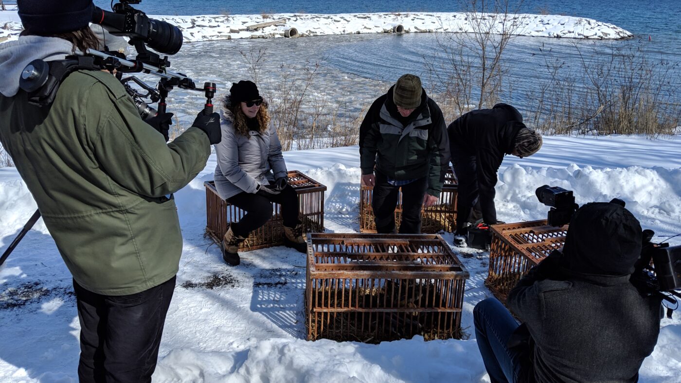 Wildlife technician, TV host and crew by a lake in winter