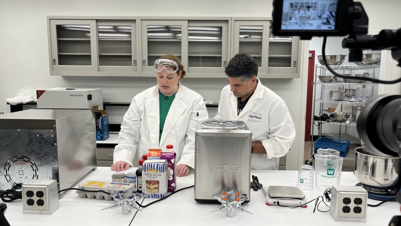 A woman and man in lab coats in a test kitchen