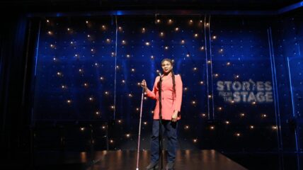 Woman Storyteller Standing on a Stage with a microphone