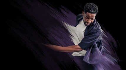 An illustration of a Black man with short Black hair and facial hair wearing a white t-shirt and purple shirt twirls his arms upward