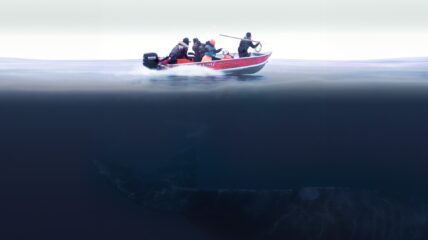 Four fishermen on a red fishing boat on the ocean