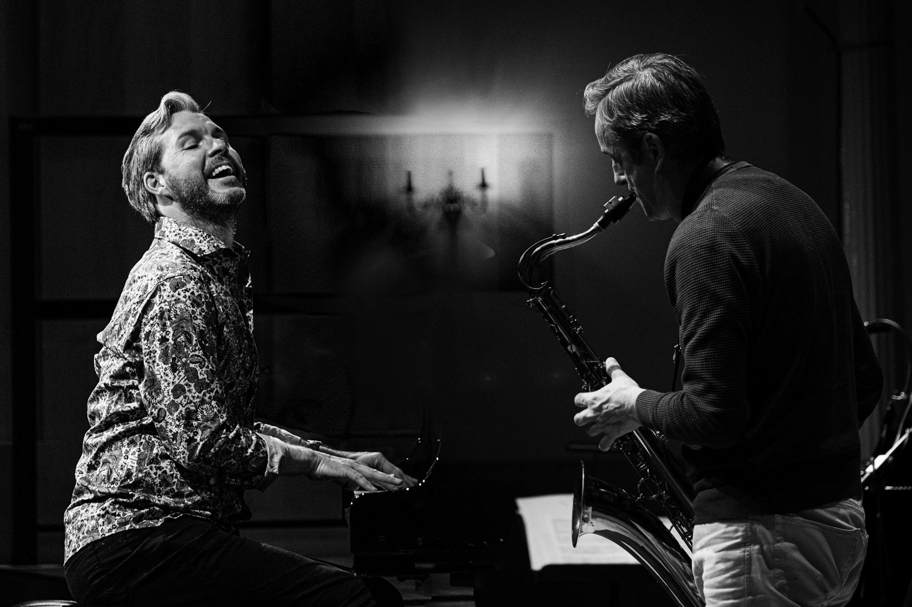 A Black and white photo of a white man playing the piano and and another white man playing the sax.