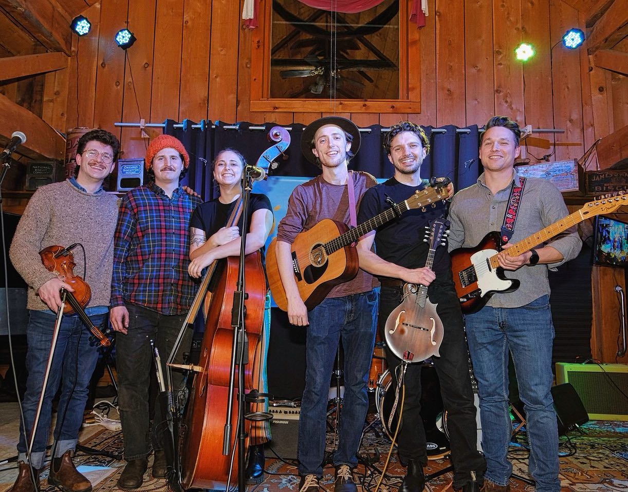 folk band with guitars shown. There are 6 members they are all white.