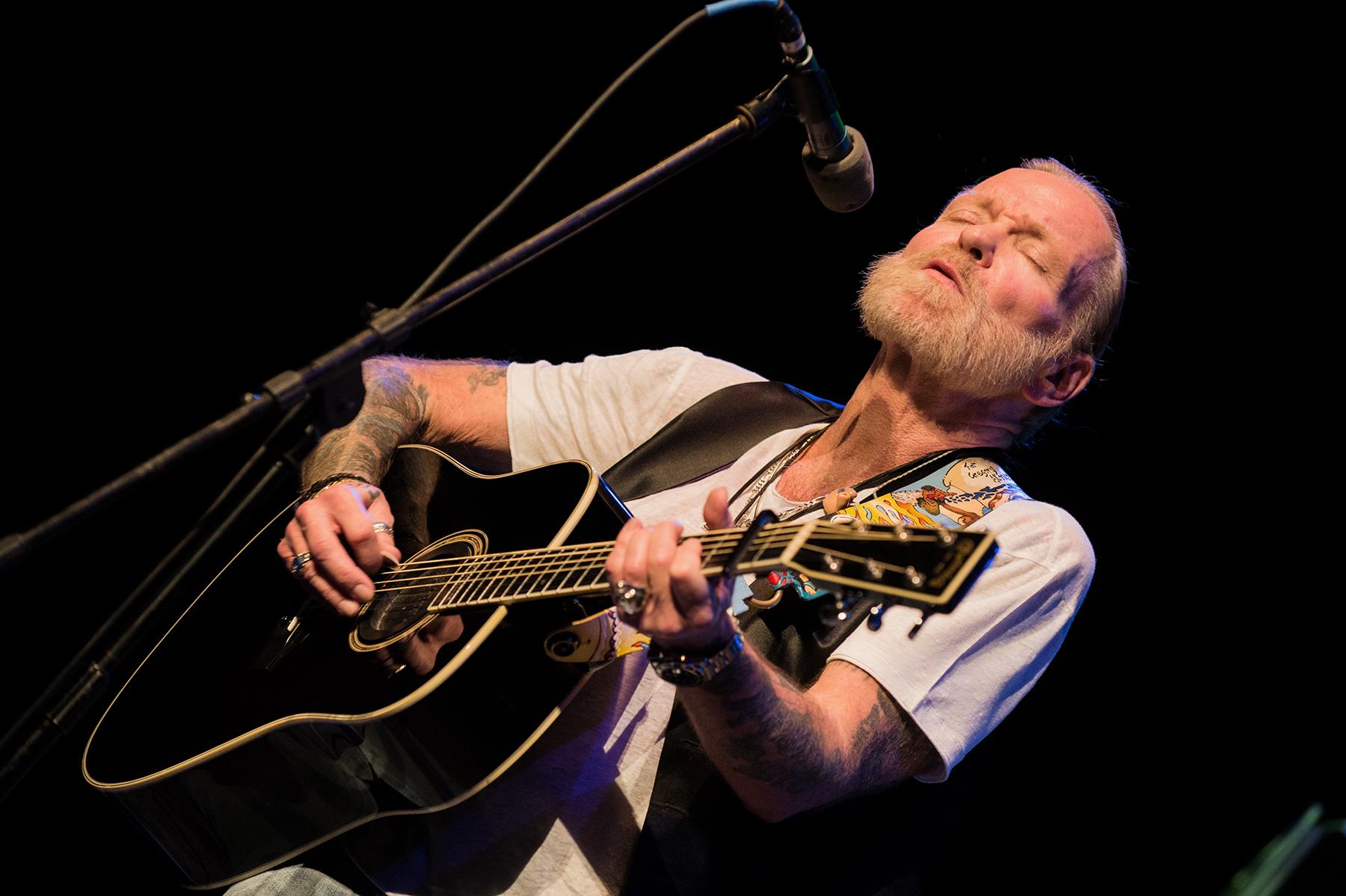 Musician Greg Allman playing the guitar on stage.