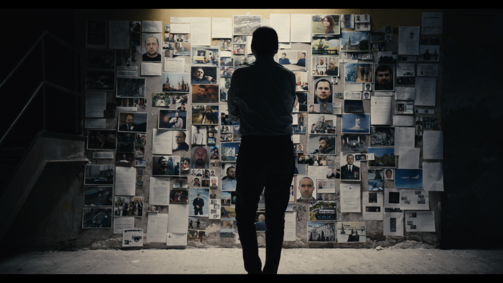 The back of man standing in front of a wall of photos and documents
