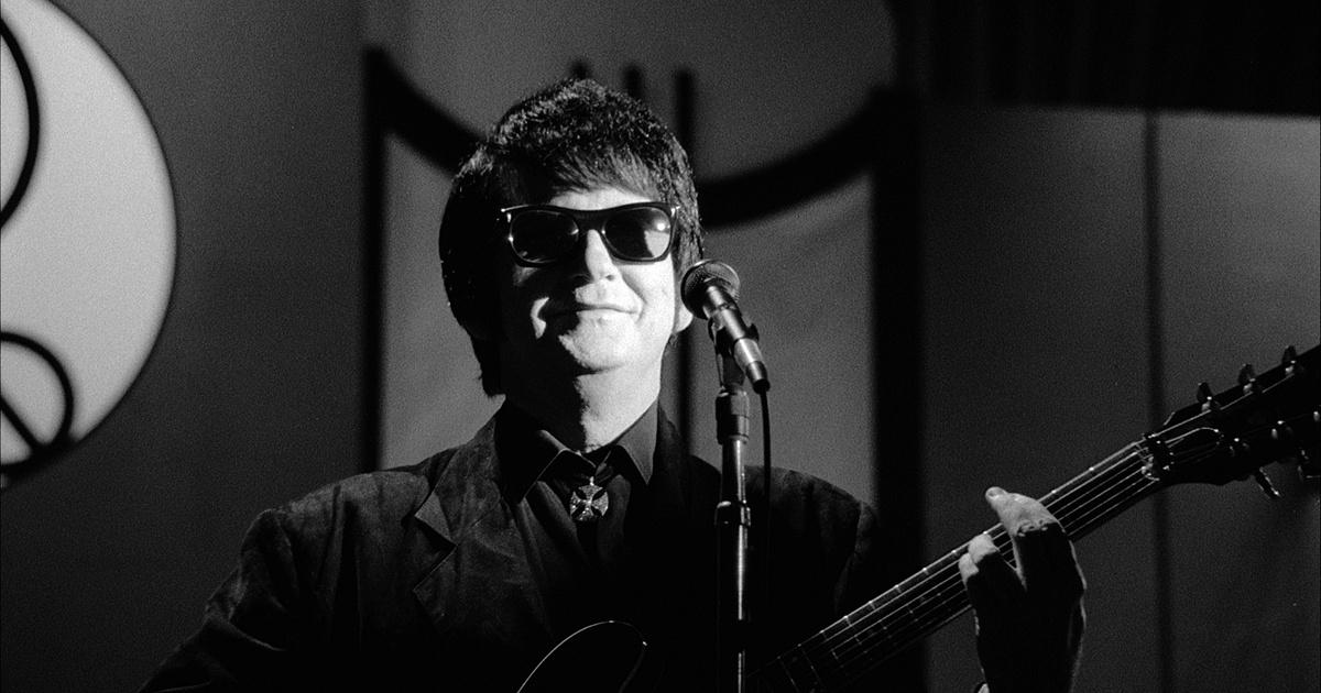 Roy Orbison on stage playing guitar.