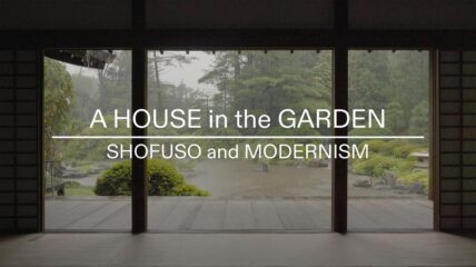 An outdoor view of a lush green yard shot from inside a house through picture windows.