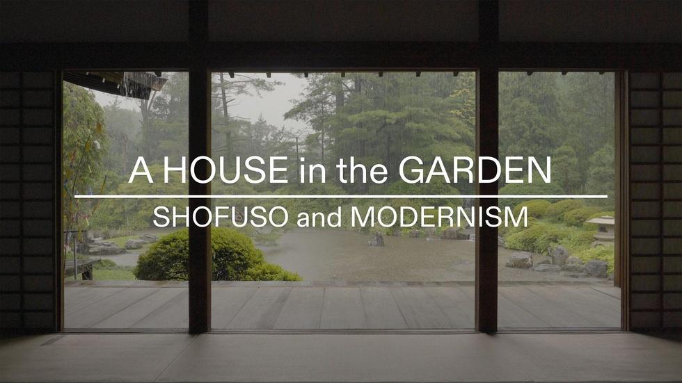 An outdoor view of a lush green yard shot from inside a house through picture windows.