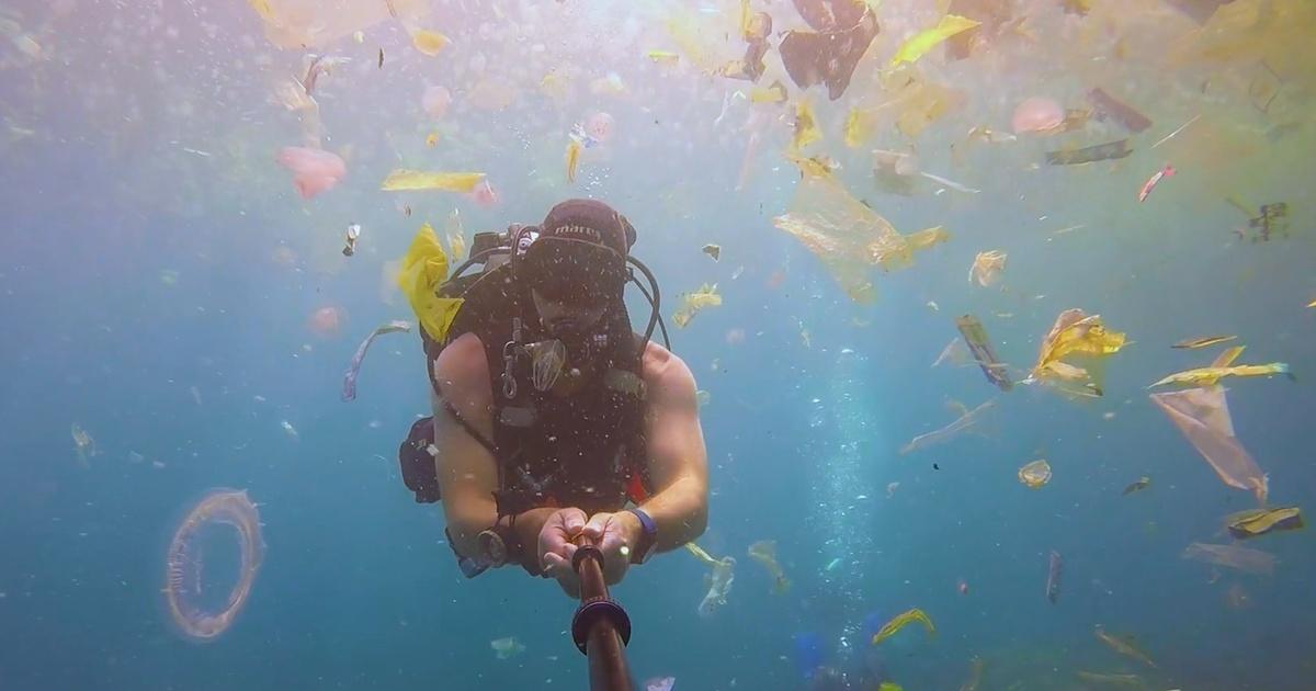 Scuba diver in a water with colorful plastic around him.