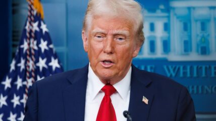 President Donald Trump in front of a flag behind a podium