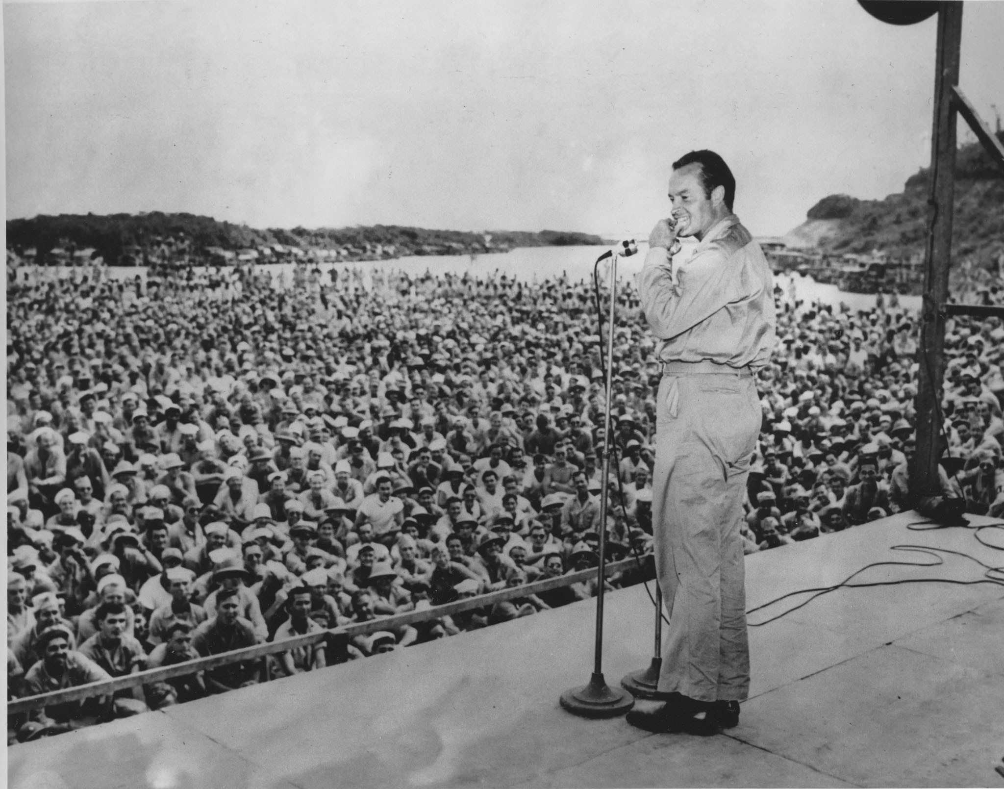 Bob Hope stand on stage in front of crowd of soldiers