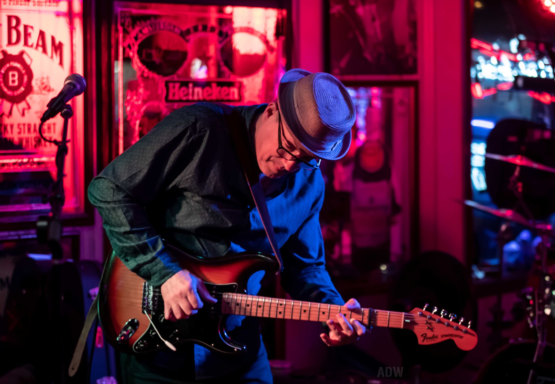 A white male wearing a dark shirt and hat playing the electric guitar.