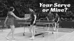 Two mixed doubles teams on a gym floor playing ping pong. The one team is shaking hands while the other team stands watching.