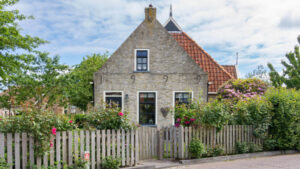 An English Tudor home surrounds by rose bushes.