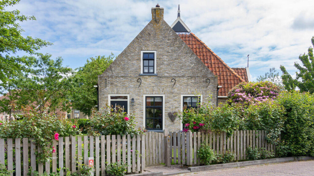 An English Tudor home surrounds by rose bushes.