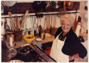 Marcella Hazan in her kitchen wearing a blue blouse and white apron