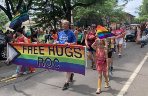 Rochester pride parade with marchers holding a sigh that reads: Free Hugs