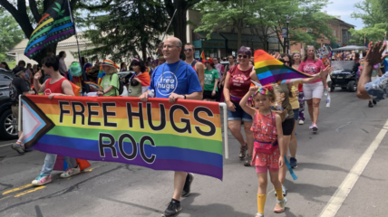 Rochester pride parade with marchers holding a sigh that reads: Free Hugs