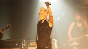 Singer Pink raising her mic to the audience as she performs on stage.
