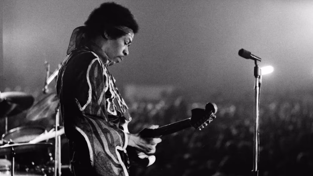 Jimi Hendrix playing an electric guitar at a concert.