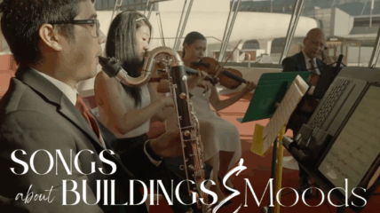 Four musicians playing music in a room with a backdrop of windows.