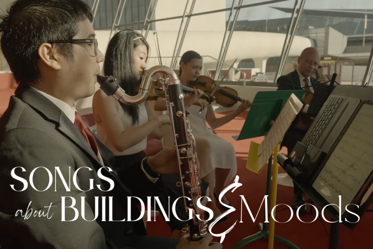 Four musicians playing music in a room with a backdrop of windows.