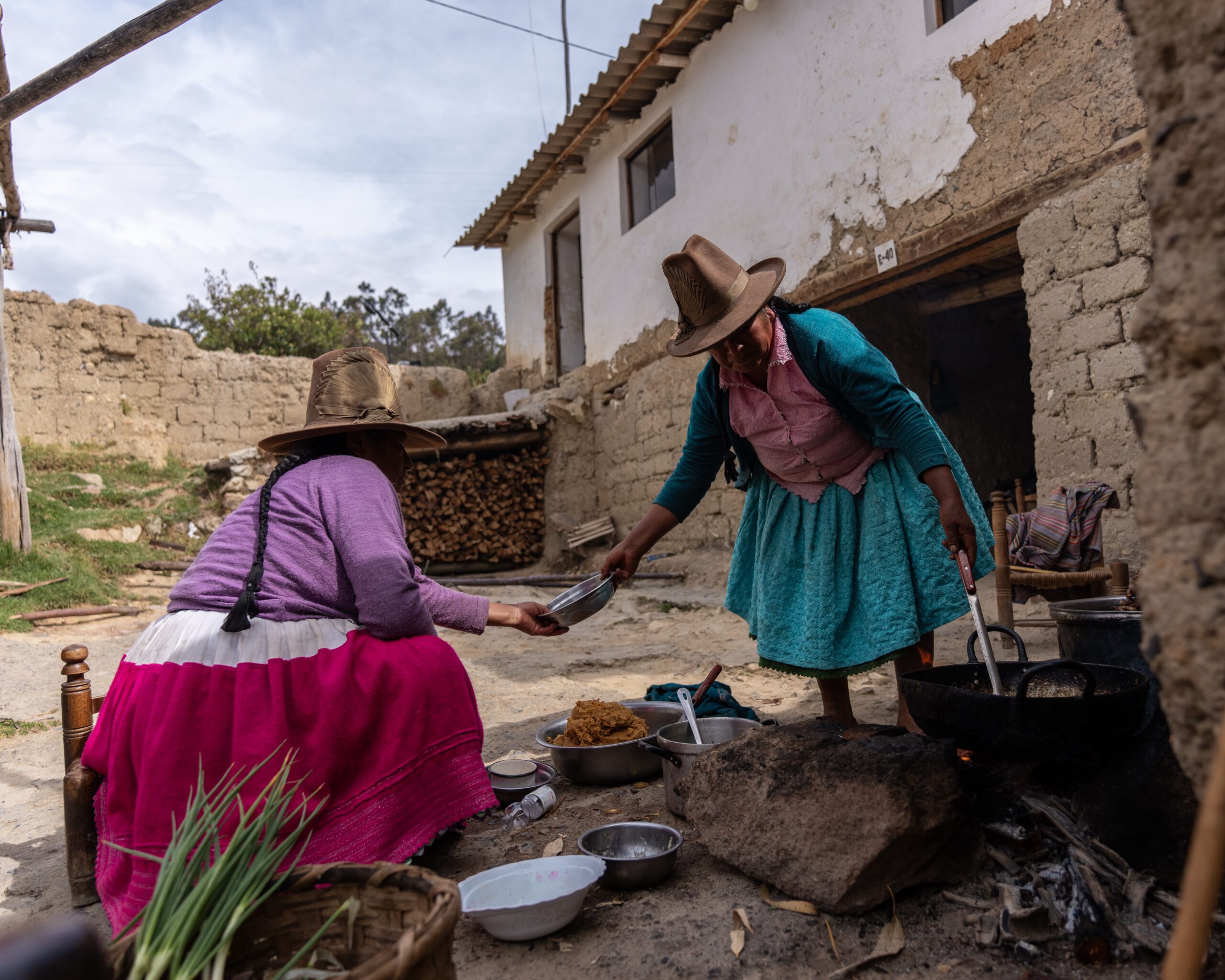 Two women preparing a meal outside on an open fire.