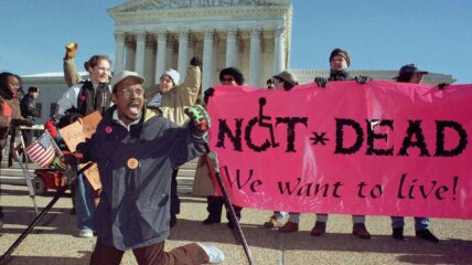 A group of people in front of the Washington DC holding a sign that reads "Not Dead Yet!"